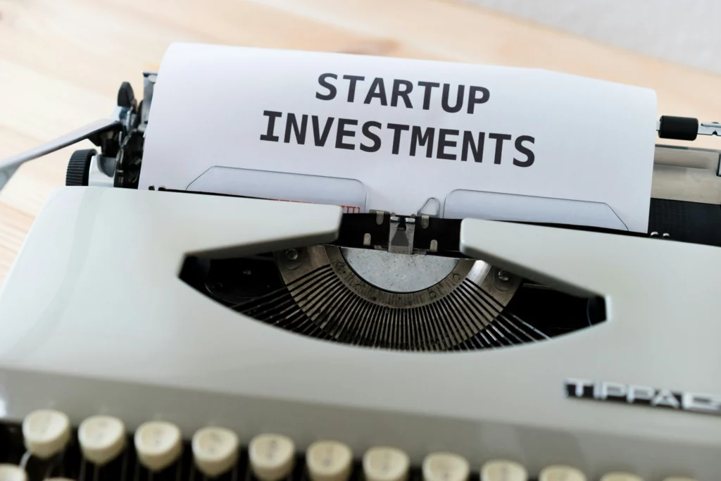 White typewriter with paper reading 'Startup Investments' on a gray background